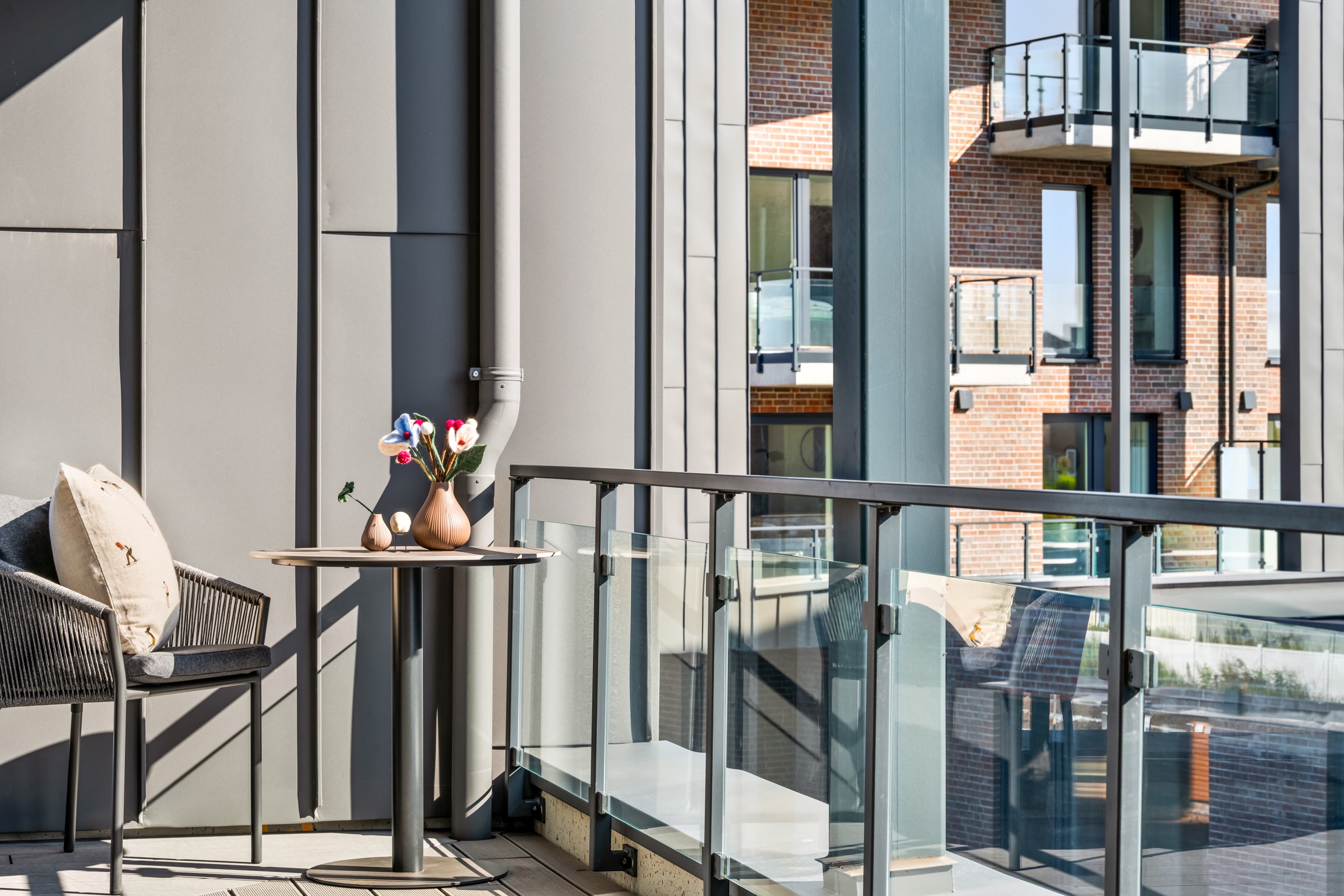 Umeblowany balkon The View ze stalowo-szklaną balustradą i widokiem na sąsiednie balkony