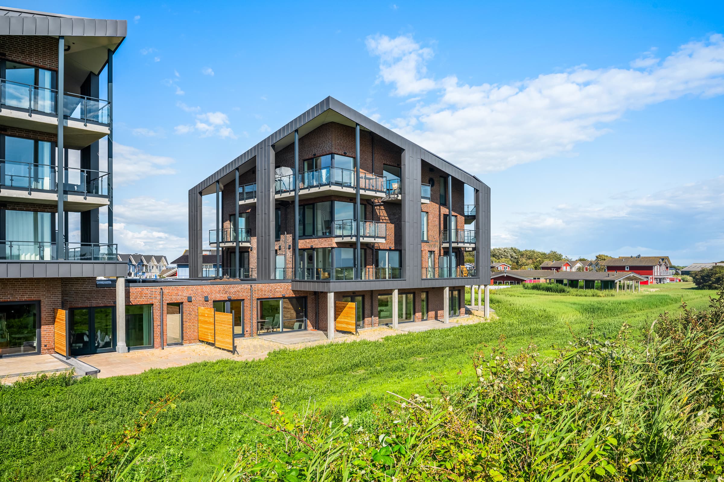 Nowy budynek apartamentowy The View w Dagebüll z balkonami i balustradami szklanymi na trzech kondygnacjach