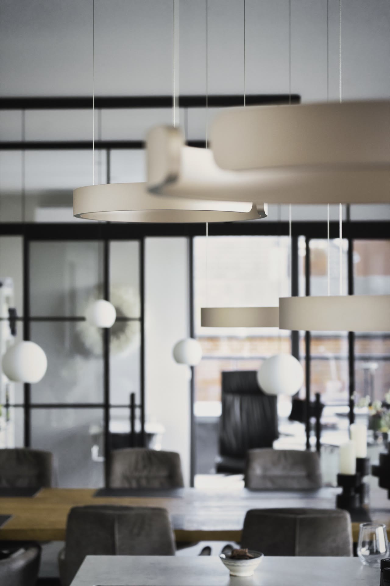 Salon z designerskimi lampami i stalowo-szklanymi drzwiami przesuwnymi dwuskrzydłowymi w tle